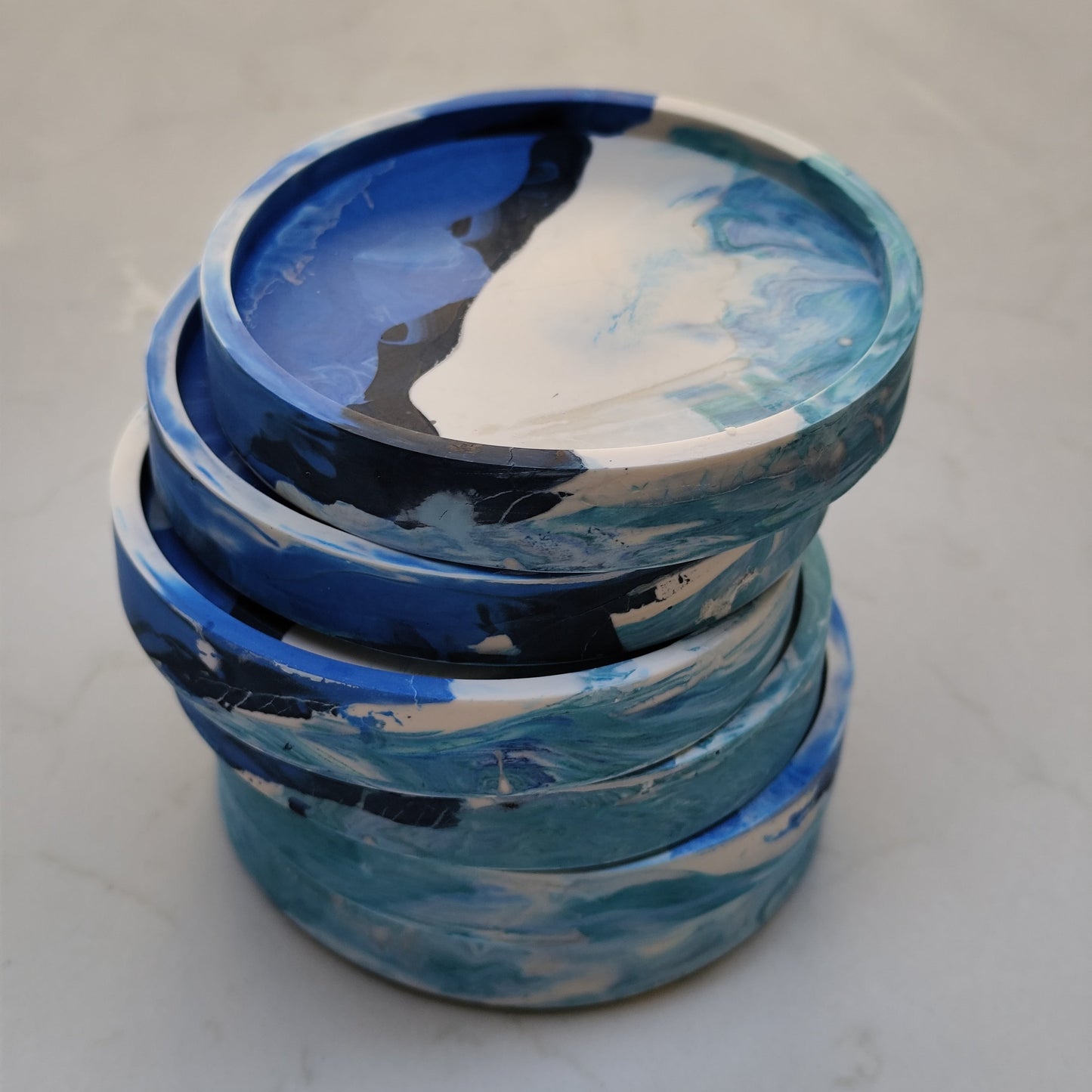 Stack of blue and white marbled containers on a light gray surface