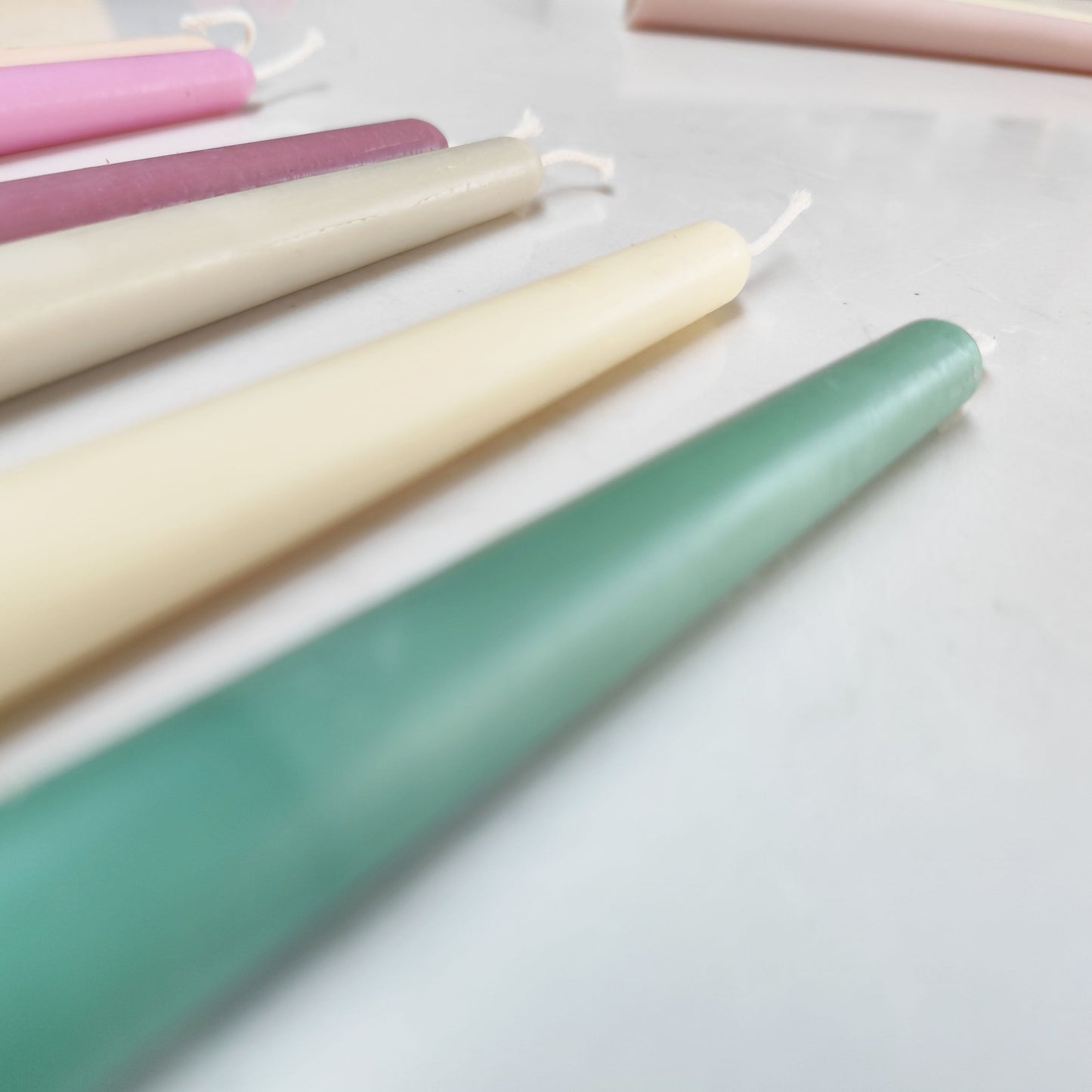 photo of different colour of the beeswax taper candles, green, white, grey, plum, pink, yellow