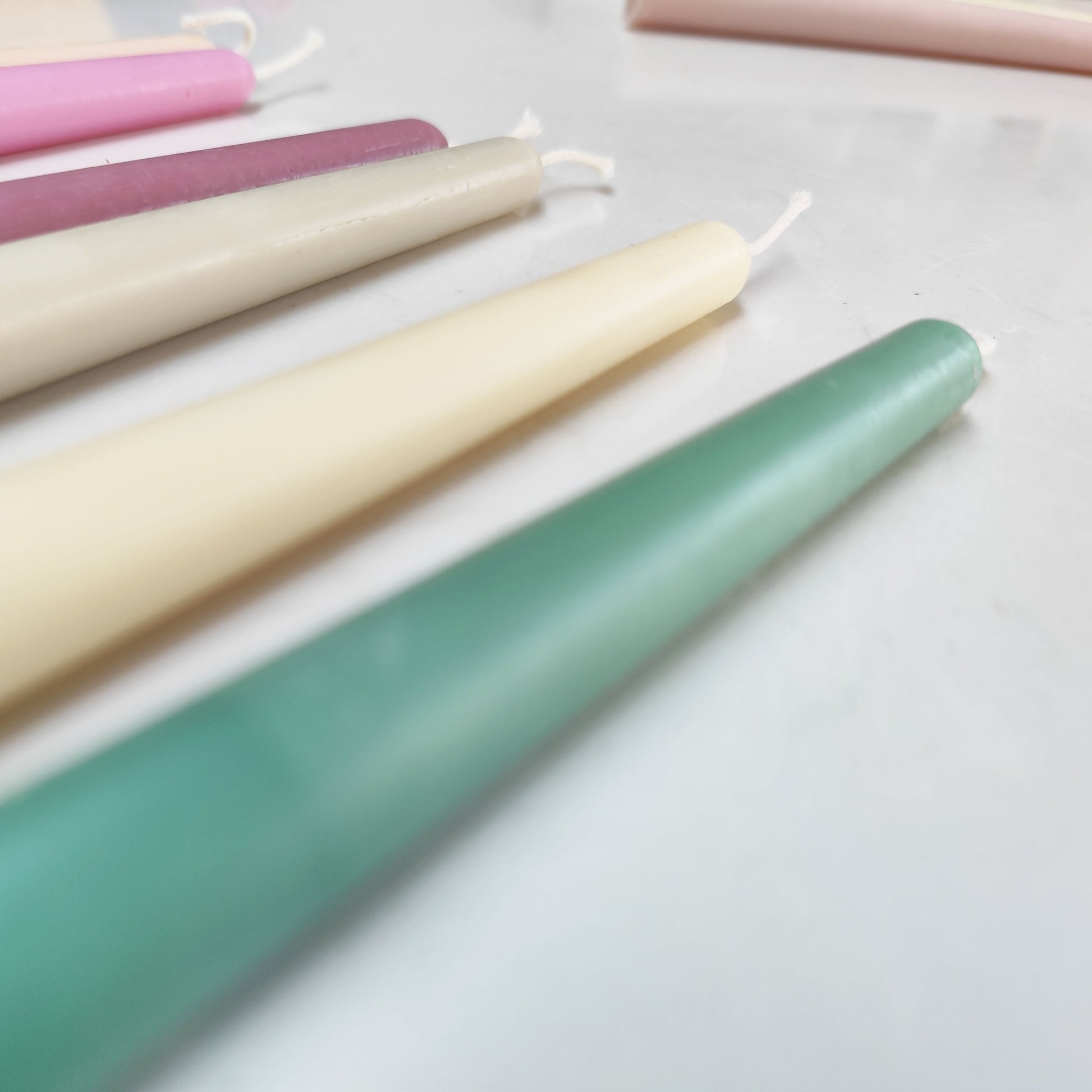 photo of different colour of the beeswax taper candles, green, white, grey, plum, pink, yellow