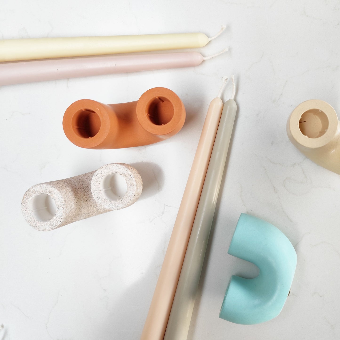 overhead group shot of beeswax candles and duo candle holder on a white background
