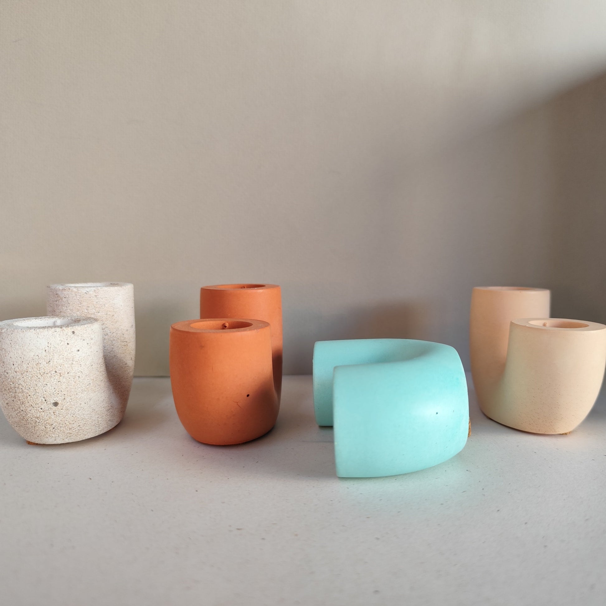 Handmade candle holders in sandstone, terracotta, mint and yellow in a stylish display