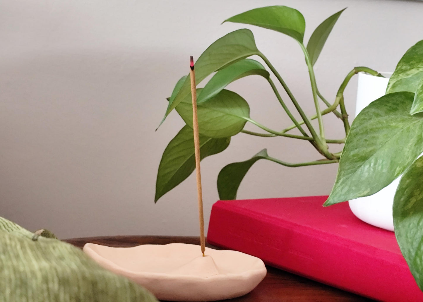 Incense stick on a small modern wooden table with green leaves in a contemporary setting