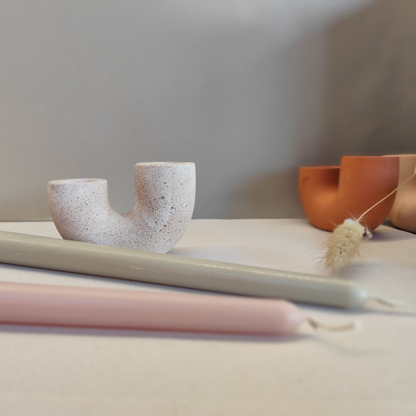 Handmade dual candle holder sandstone colour on neutral background with two beeswax candles infront