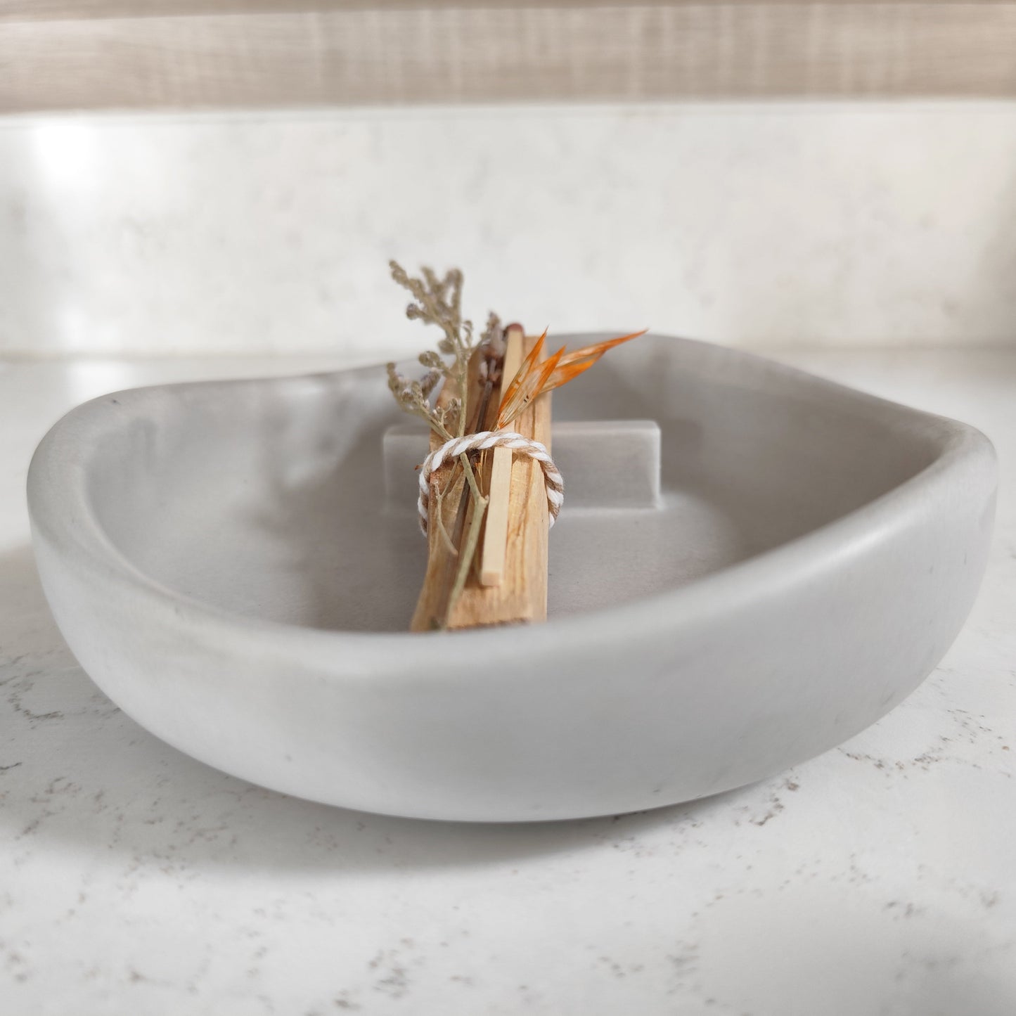 Hand crafted palo santo burner in grey with a stick and dried flowers placed on top side view