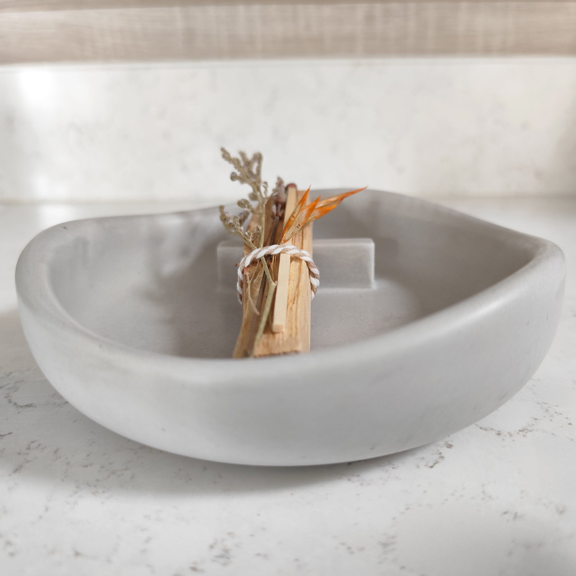 Hand crafted palo santo burner in grey with a stick and dried flowers placed on top side view