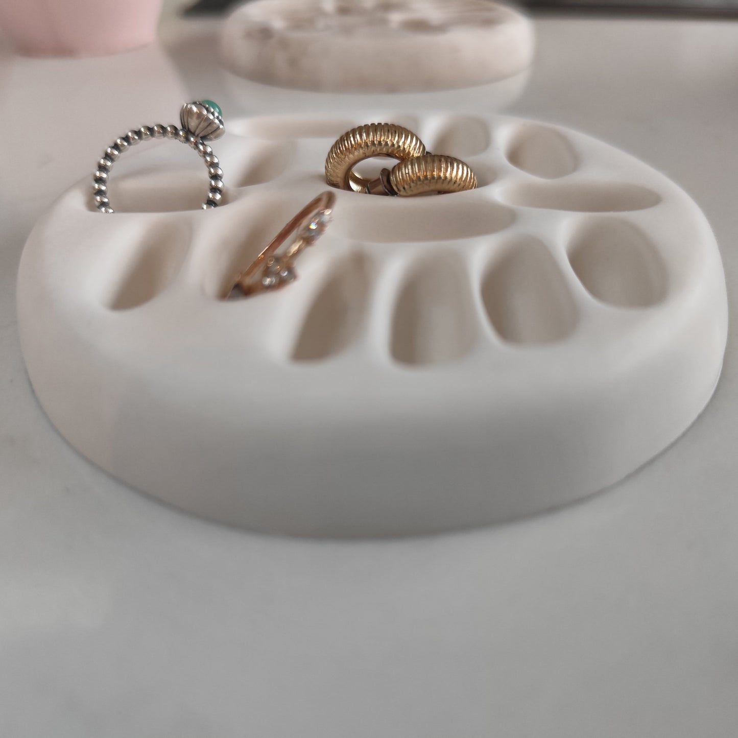 White ring dish holding two rings and a pair of earrings