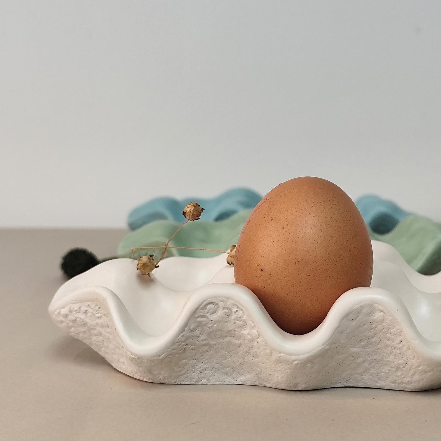 Brown egg in a white egg tray on a neutral background with other trays behind