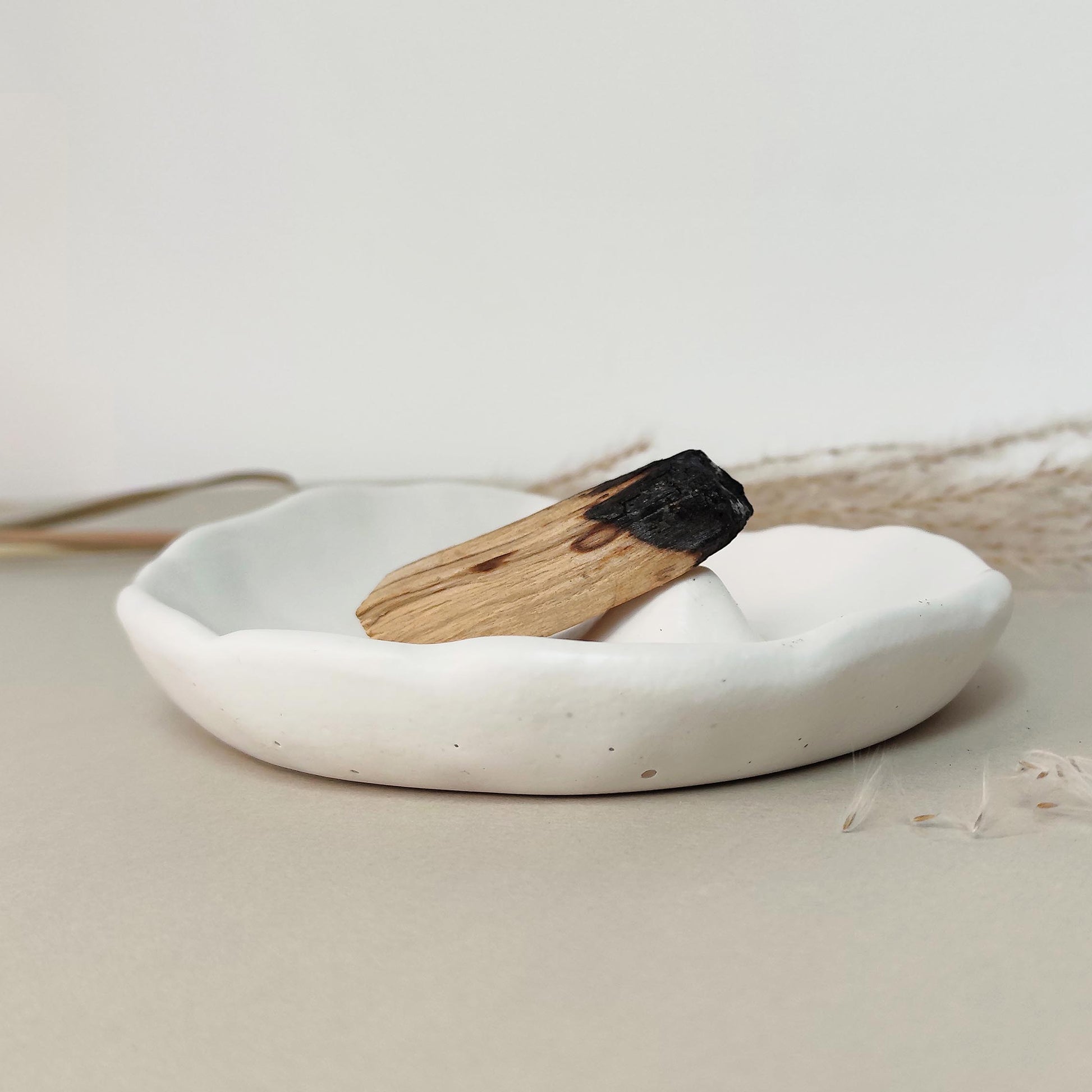 handmade burner dish with palo santo stick on a neutral background